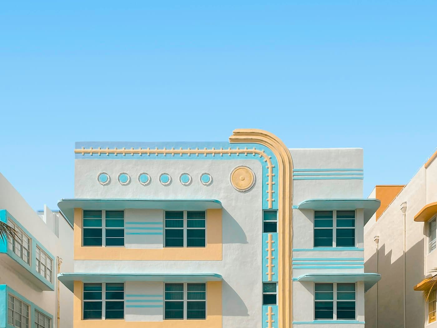 A pastel Art Deco hotel facade in Miami Beach, mint and cream against a clear sky.
